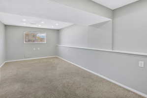 Spacious carpeted room featuring recessed lighting, a window, and light gray walls with white trim