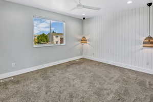 Interior room featuring plush gray carpeting, a window with white trim, and a white shiplap accent wall