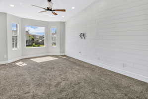 Room featuring a bay window, shiplap accent wall, vaulted ceiling, recessed lighting, and a ceiling fan with wood-finish blades
