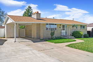 Brick exterior ranch-style home featuring a brown shingle roof and an attached carport