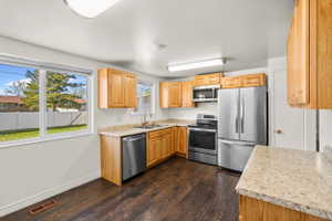 Kitchen with wood-finish flooring, light wood cabinetry, and speckled countertops