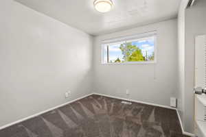 Bright room featuring a large window, neutral wall paint, patterned carpet, and a ceiling-mounted light fixture