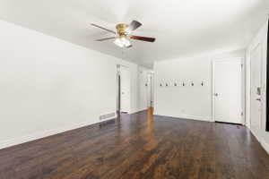 Expansive room featuring wood-finish flooring, white baseboards, and bright white walls