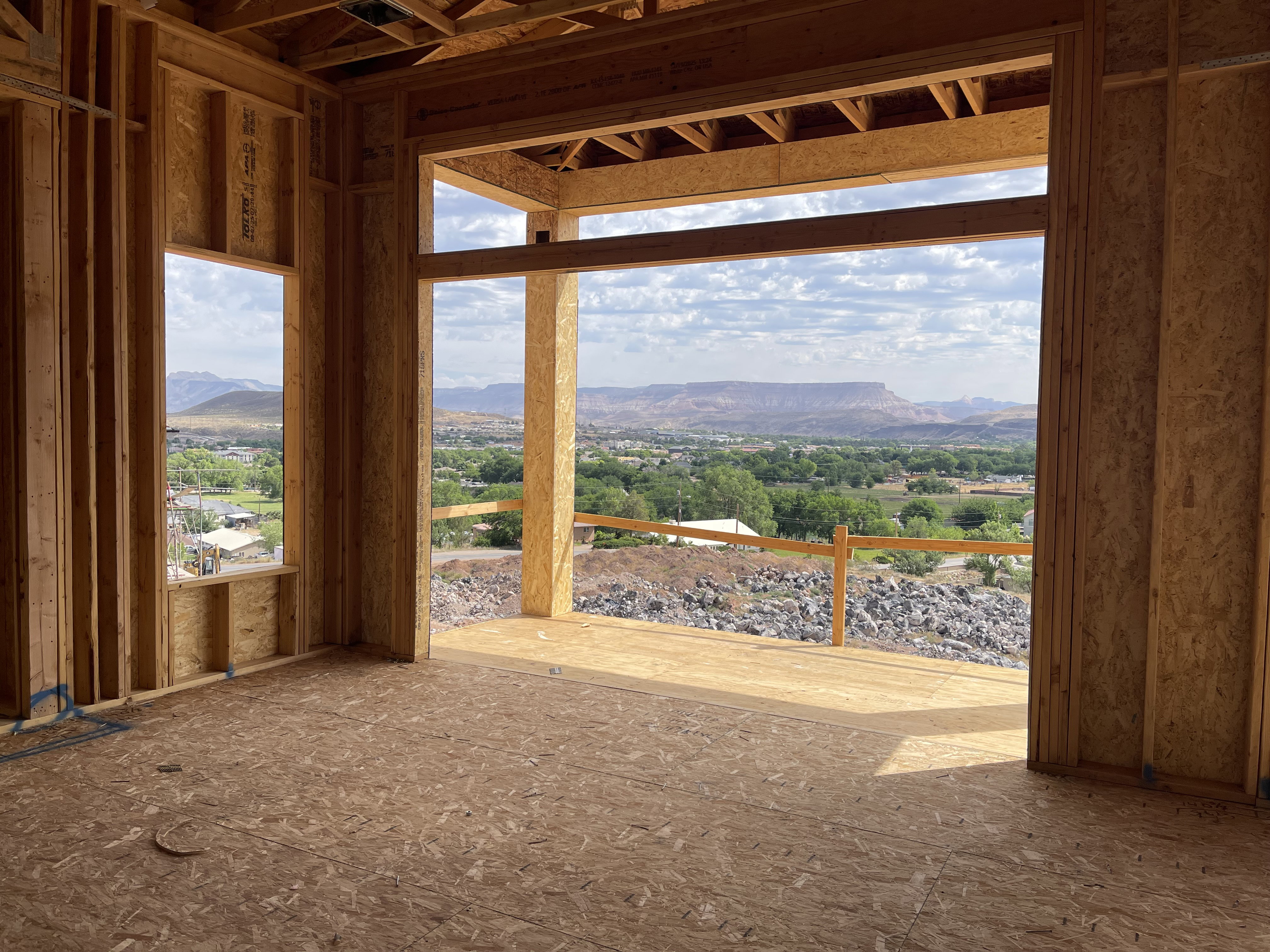 Expansive outdoor living area, showcasing a panoramic mountain and valley backdrop, with a generous window opening and natural wood framing