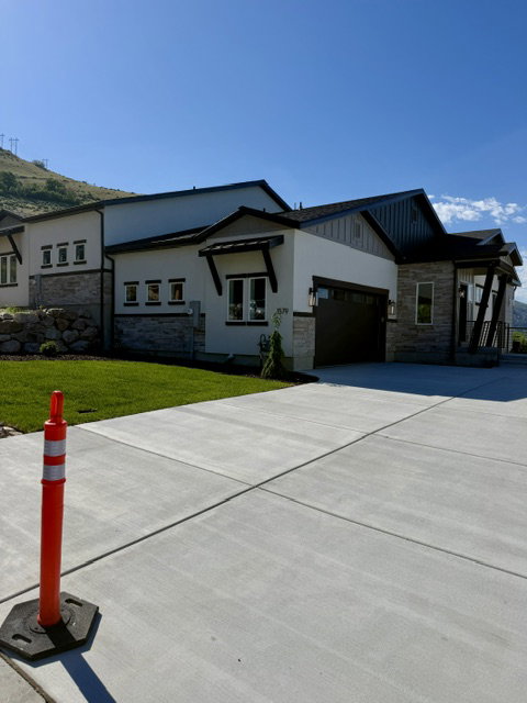 Contemporary residence featuring a two-car garage, stone and stucco facade, dark trim accents, and a sloped roofline