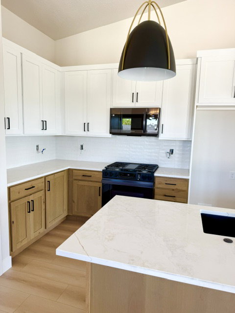 Modern kitchen featuring white upper cabinetry, wood-finish lower cabinetry, and light-toned countertops