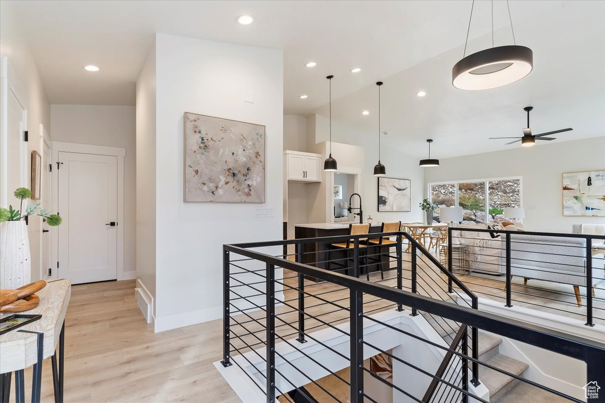 Upper-level landing featuring a modern metal rod railing system, wood-finish flooring, and recessed lighting