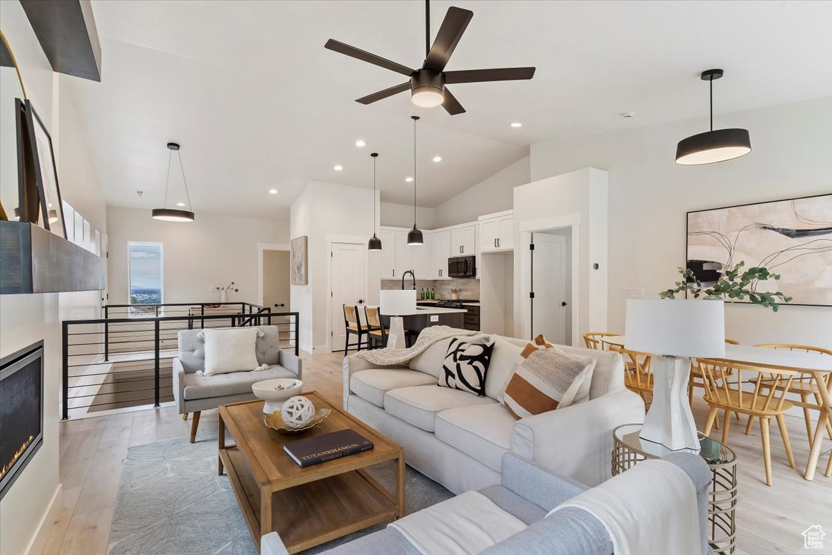Open-concept living space featuring wood-finish flooring, vaulted ceilings, and recessed lighting