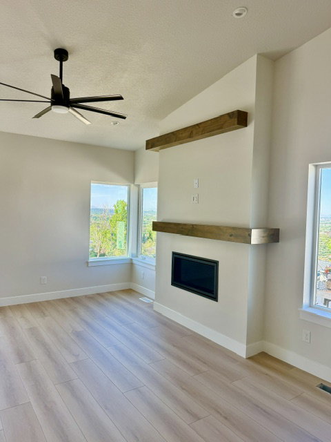 Living area featuring light wood-finish flooring and a contemporary fireplace with a dark metal insert and a wood mantel
