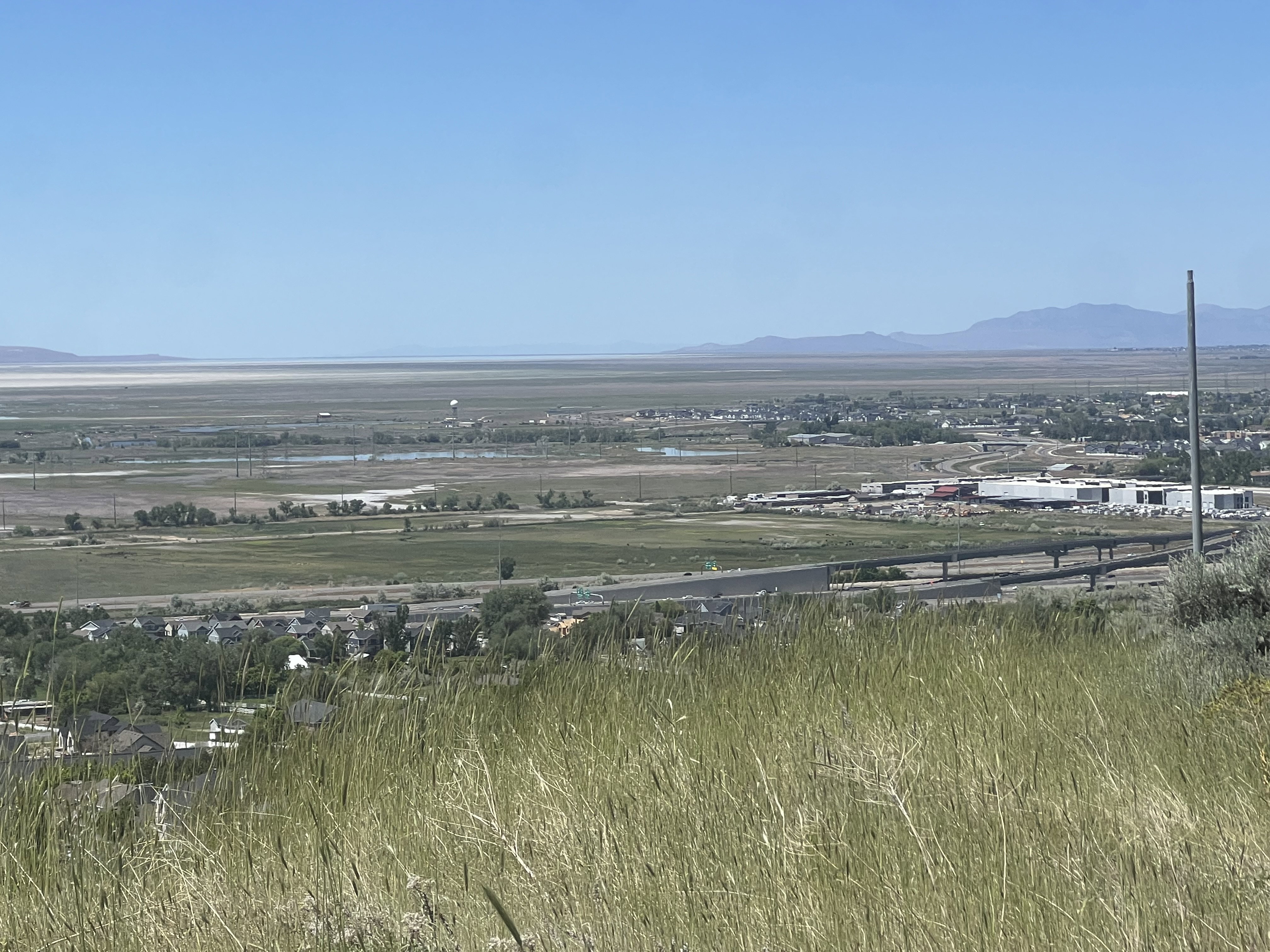 Expansive landscape featuring distant mountains, a prominent body of water, and a wide-open sky