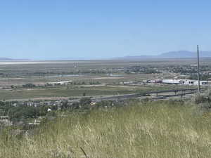 Expansive landscape featuring distant mountains, a prominent body of water, and a wide-open sky
