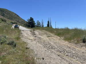 Expansive undeveloped lot featuring a gradual incline, natural terrain, and distant mountainous backdrop