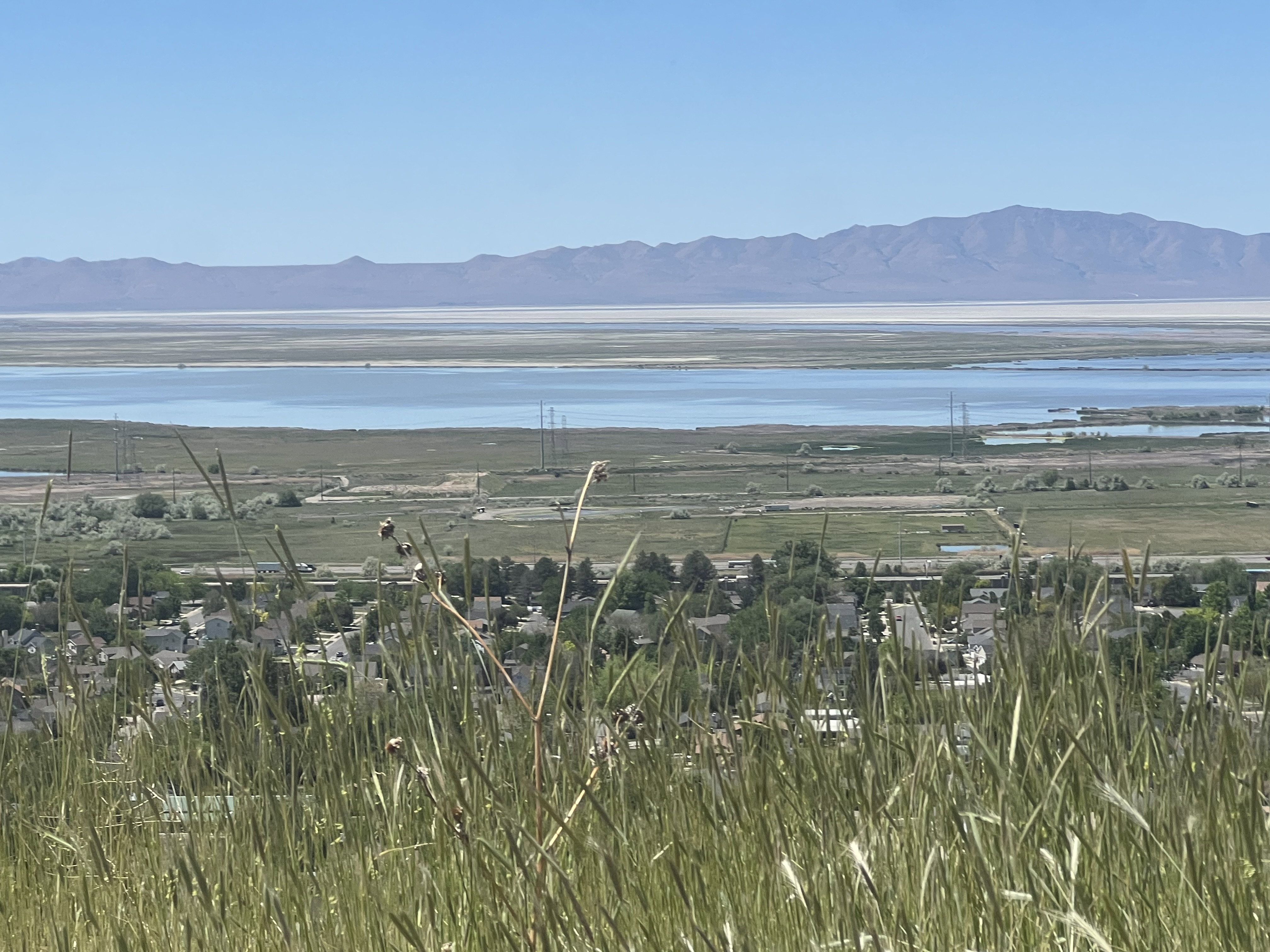Scenic landscape featuring distant mountains, a large body of water, and a residential area with visible rooftops