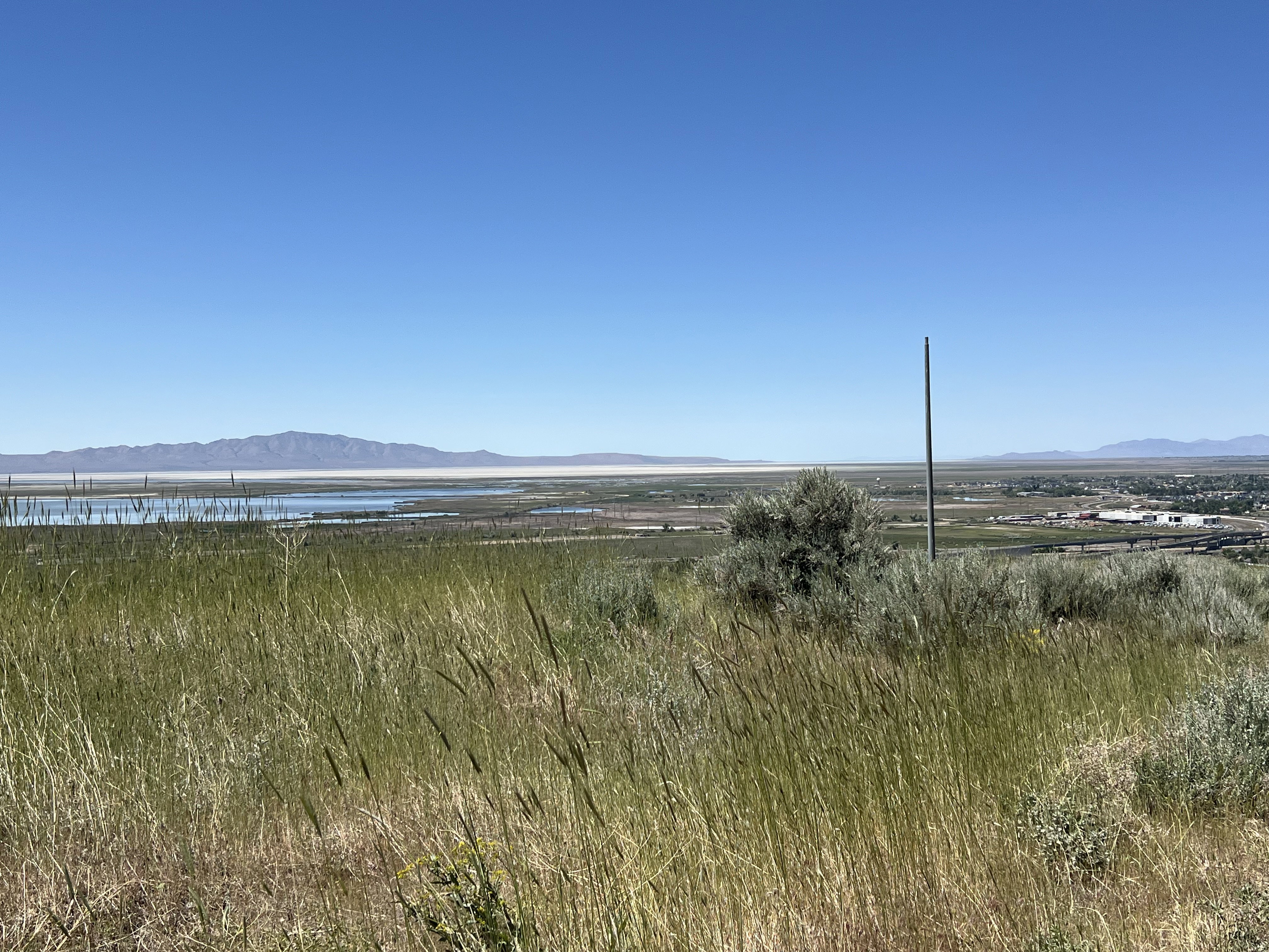 Expansive landscape featuring distant mountains, a body of water, and broad plains