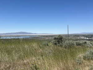Expansive landscape featuring distant mountains, a body of water, and broad plains