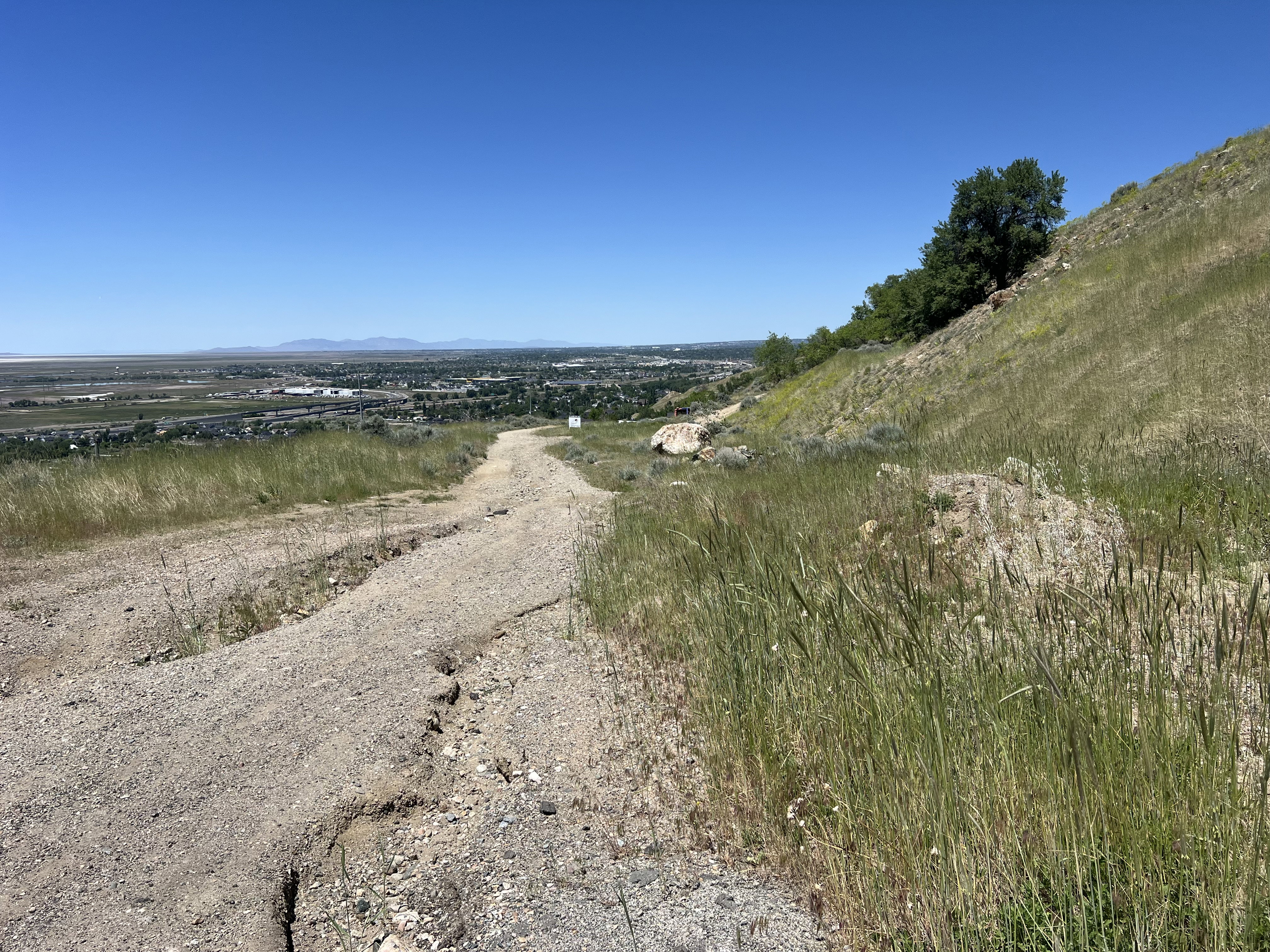 Expansive hillside property featuring a gravel path and distant urban landscape