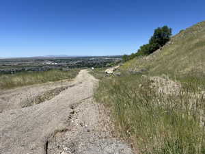 Expansive hillside property featuring a gravel path and distant urban landscape