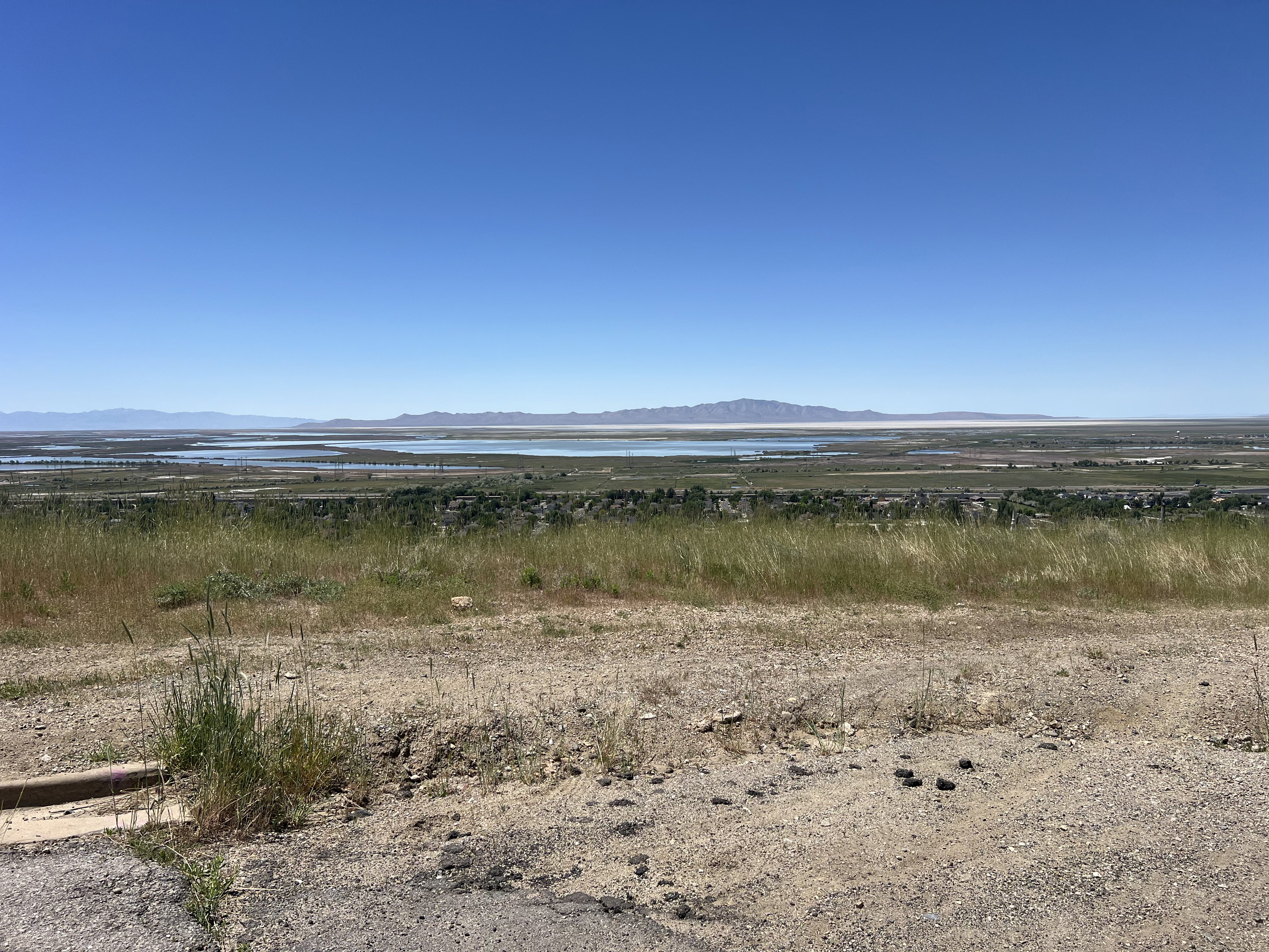 Expansive territorial landscape featuring distant water bodies and mountain ranges under a clear sky
