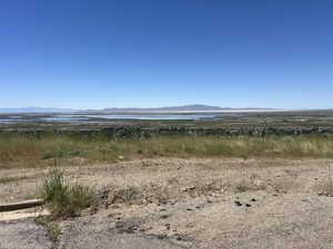 Expansive territorial landscape featuring distant water bodies and mountain ranges under a clear sky