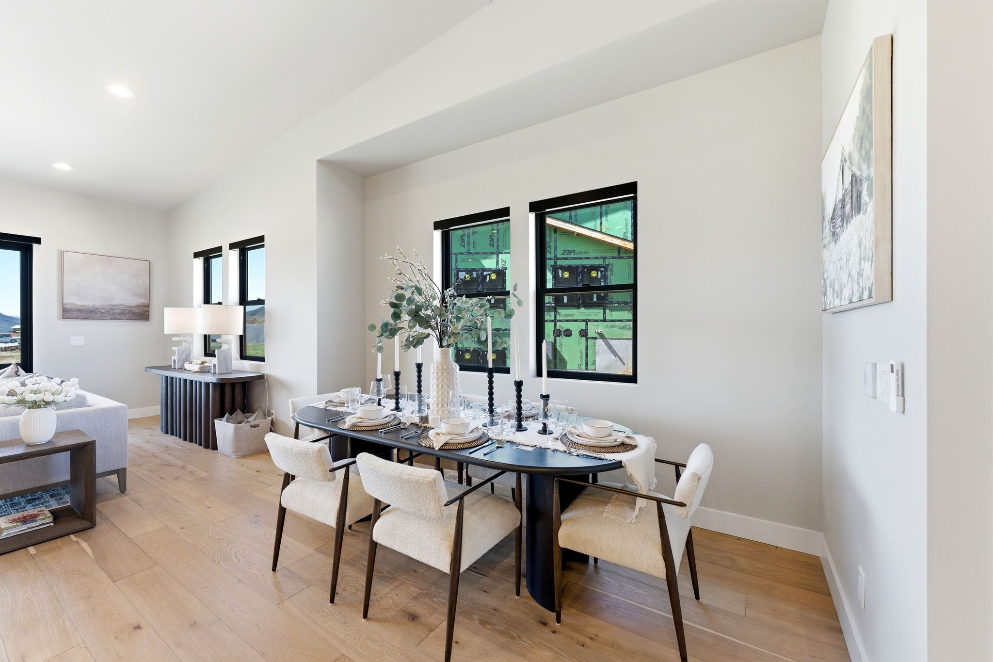 Open-concept living space featuring wood-finish flooring, recessed lighting, and multiple windows with black trim