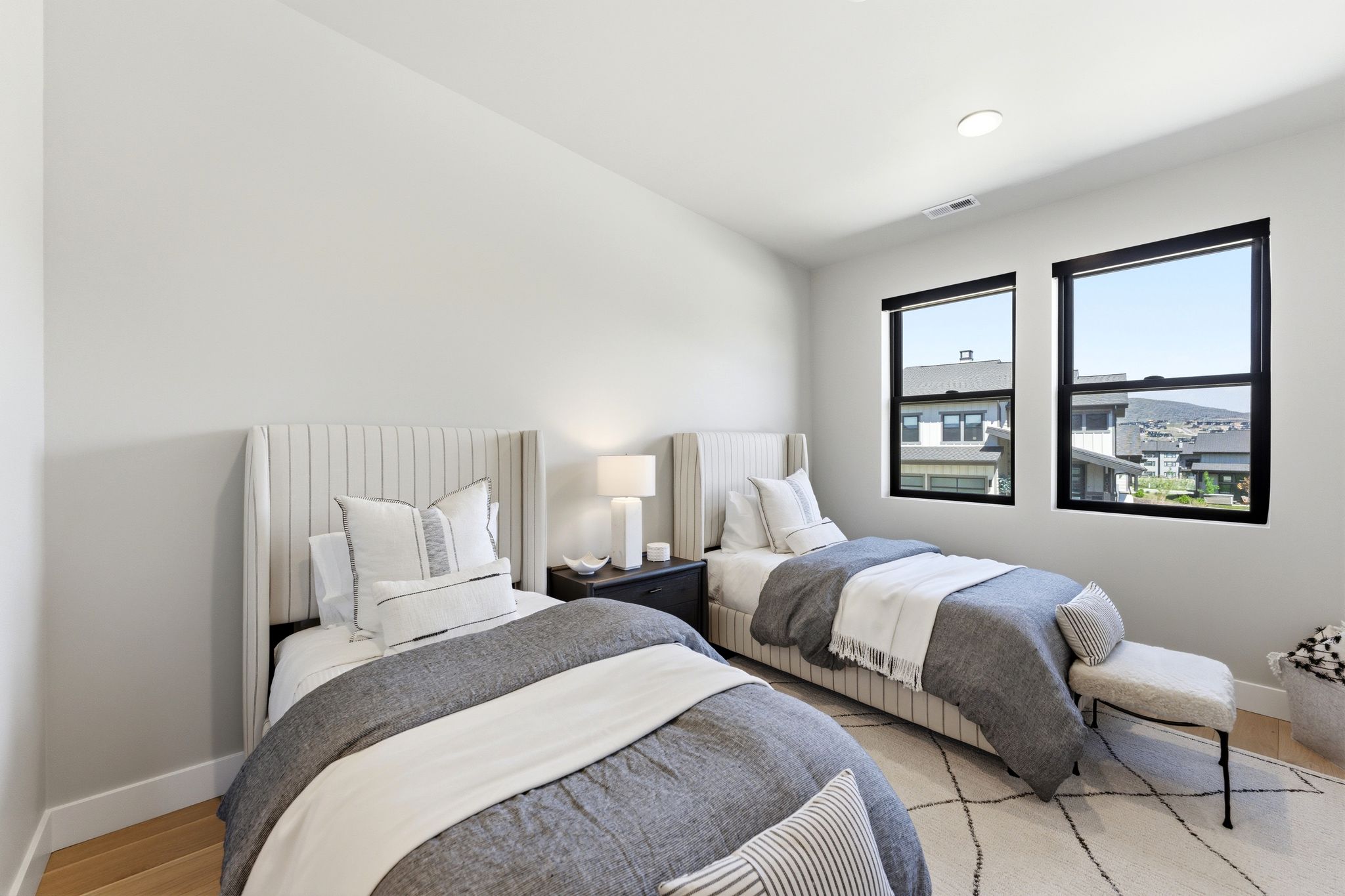 Contemporary room featuring two distinct upholstered wingback beds, recessed lighting, and light wood-finish flooring
