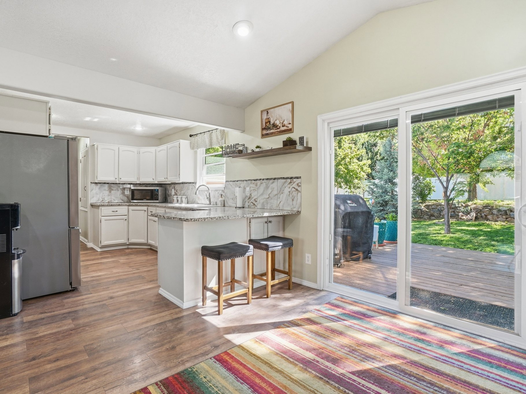 Kitchen featuring white cabinetry, wood-finish flooring, and a breakfast bar with stone-finish countertops