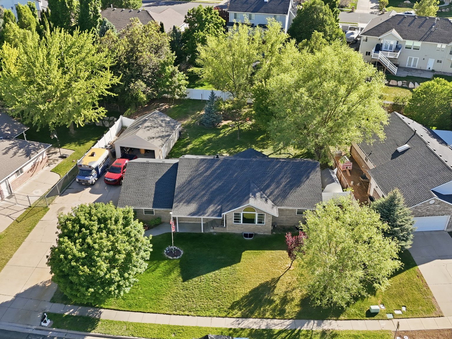 Ranch-style residence featuring a prominent front lawn, mature landscaping, and a covered front porch
