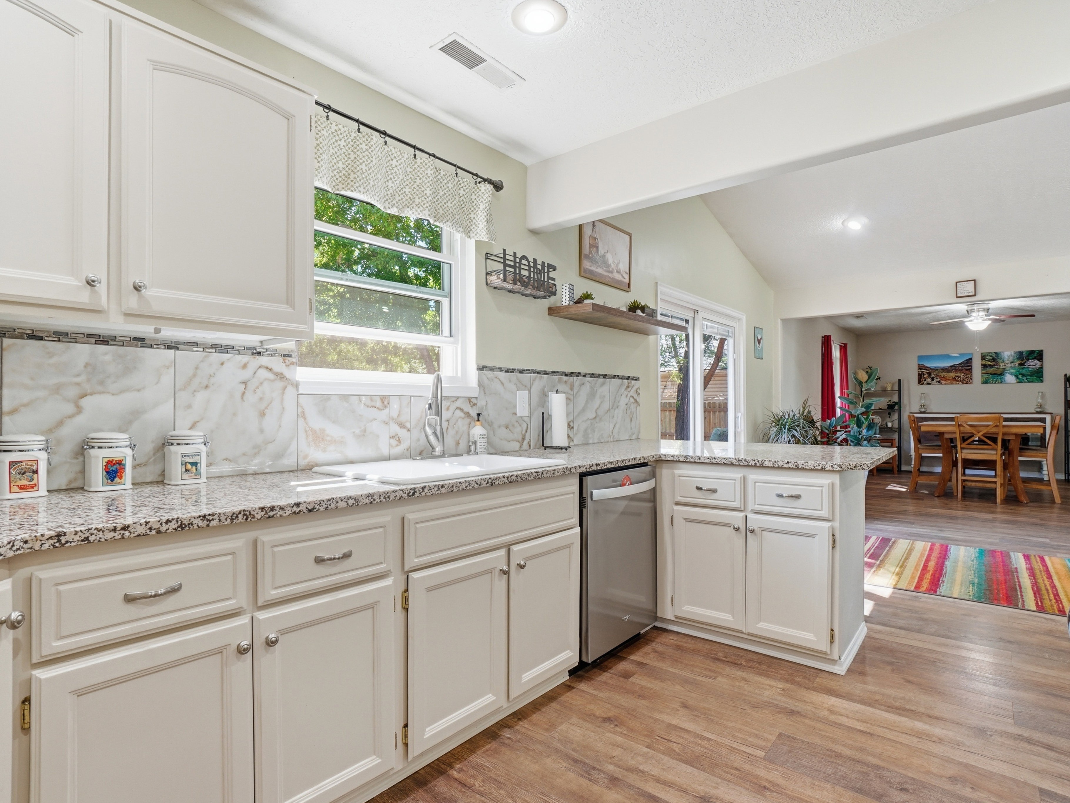 Kitchen featuring light-toned cabinetry, granite-finish countertops, and a tiled backsplash
