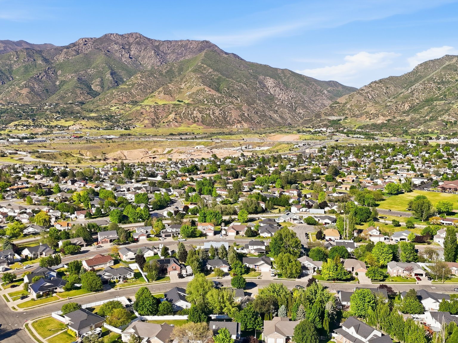 Community setting with a backdrop of verdant mountains, mature trees, and residential architecture