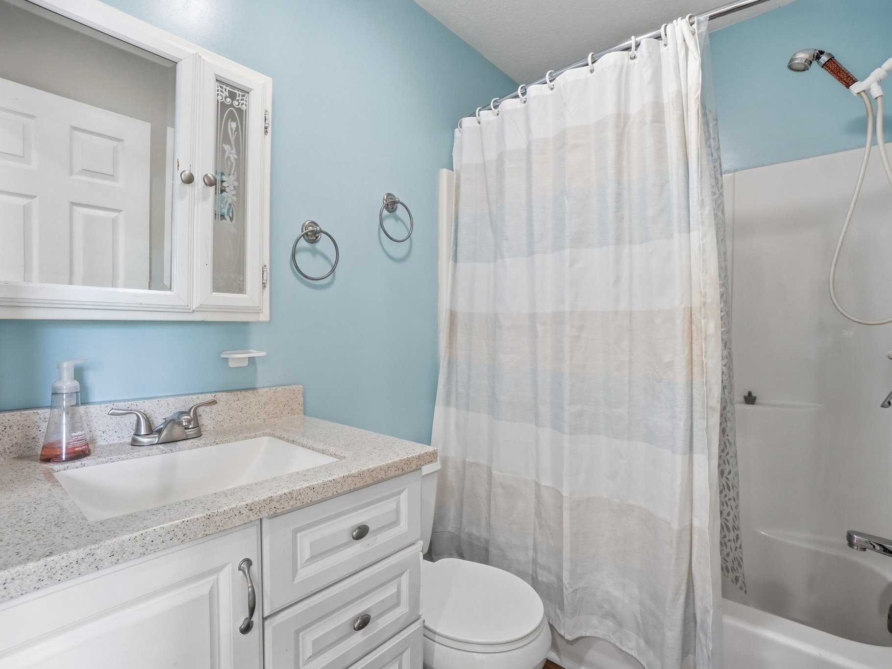 Bathroom featuring a white vanity with a speckled countertop, an integrated sink, and white cabinetry