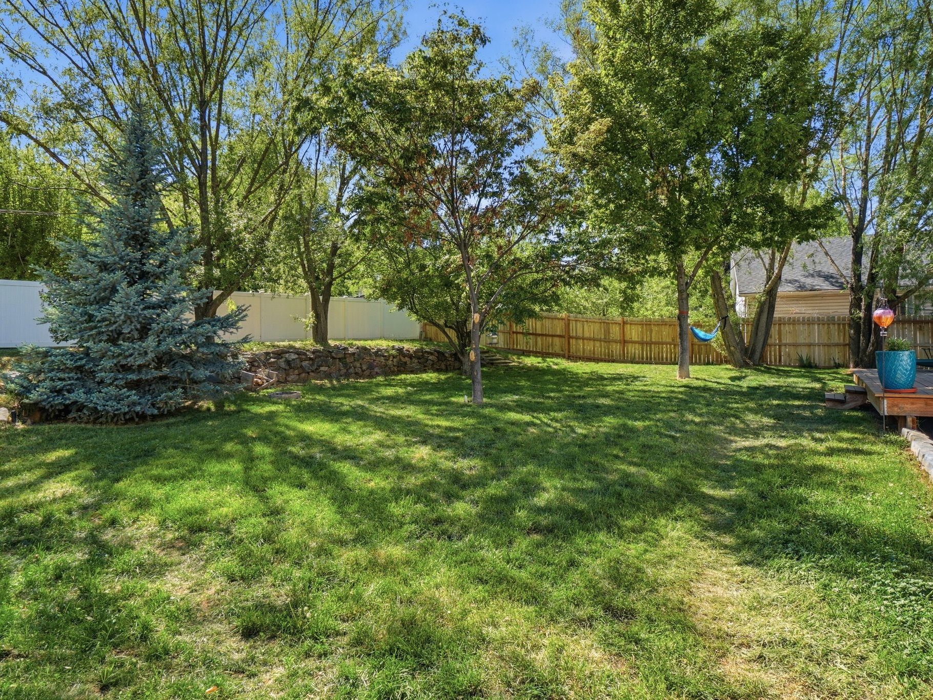 Expansive green yard with mature trees and a wooden deck