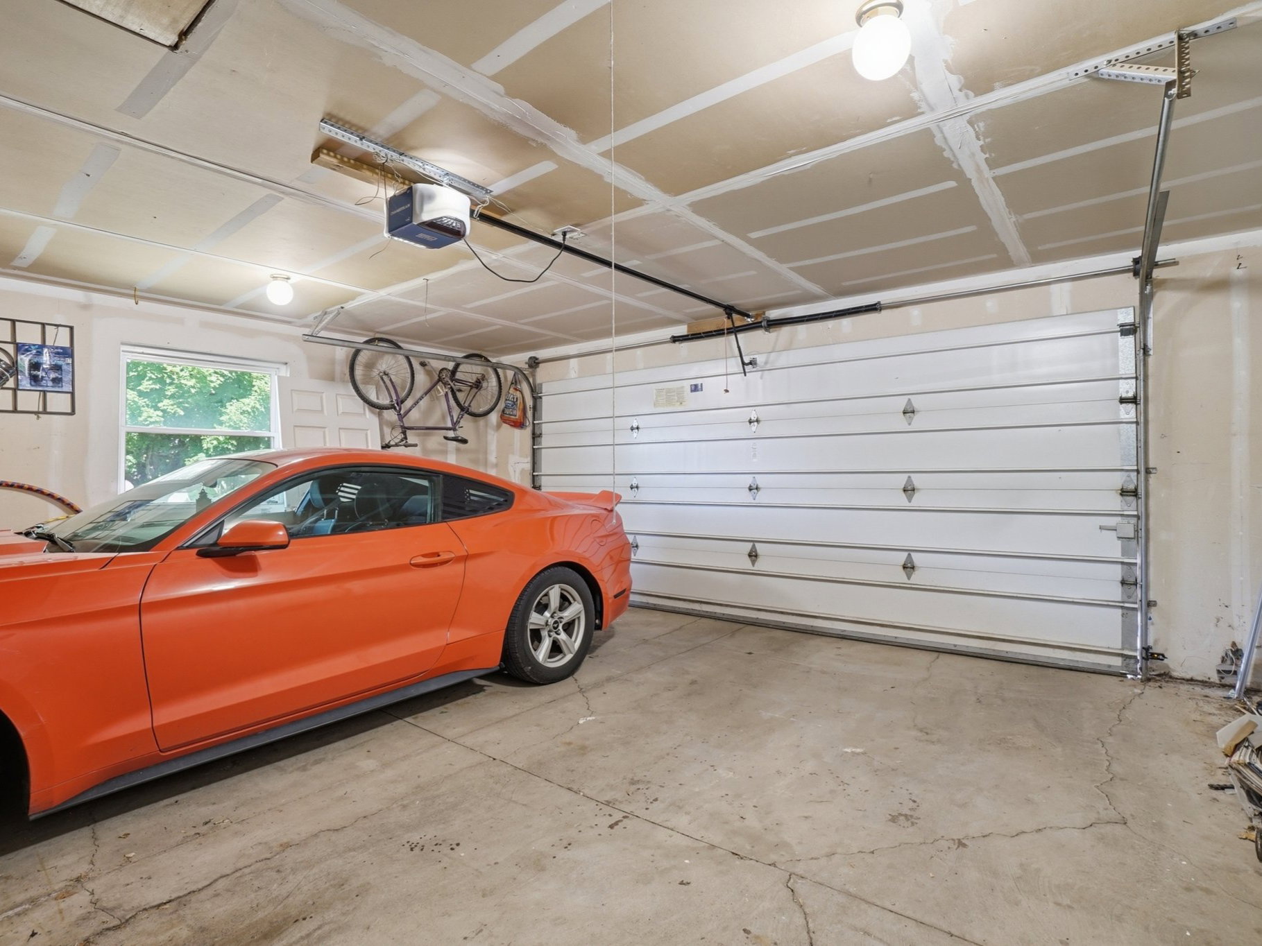 Attached two-car garage with a single window, concrete flooring, and an automatic garage door opener