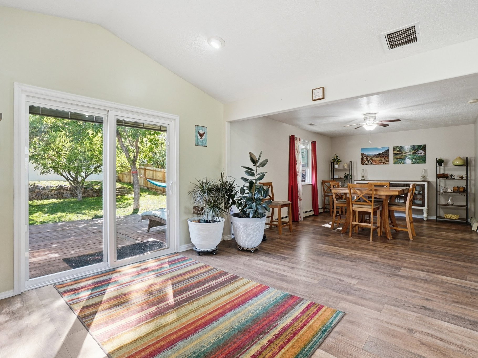 Spacious interior featuring wood-finish flooring, vaulted ceilings, and a sliding glass door to an outdoor deck