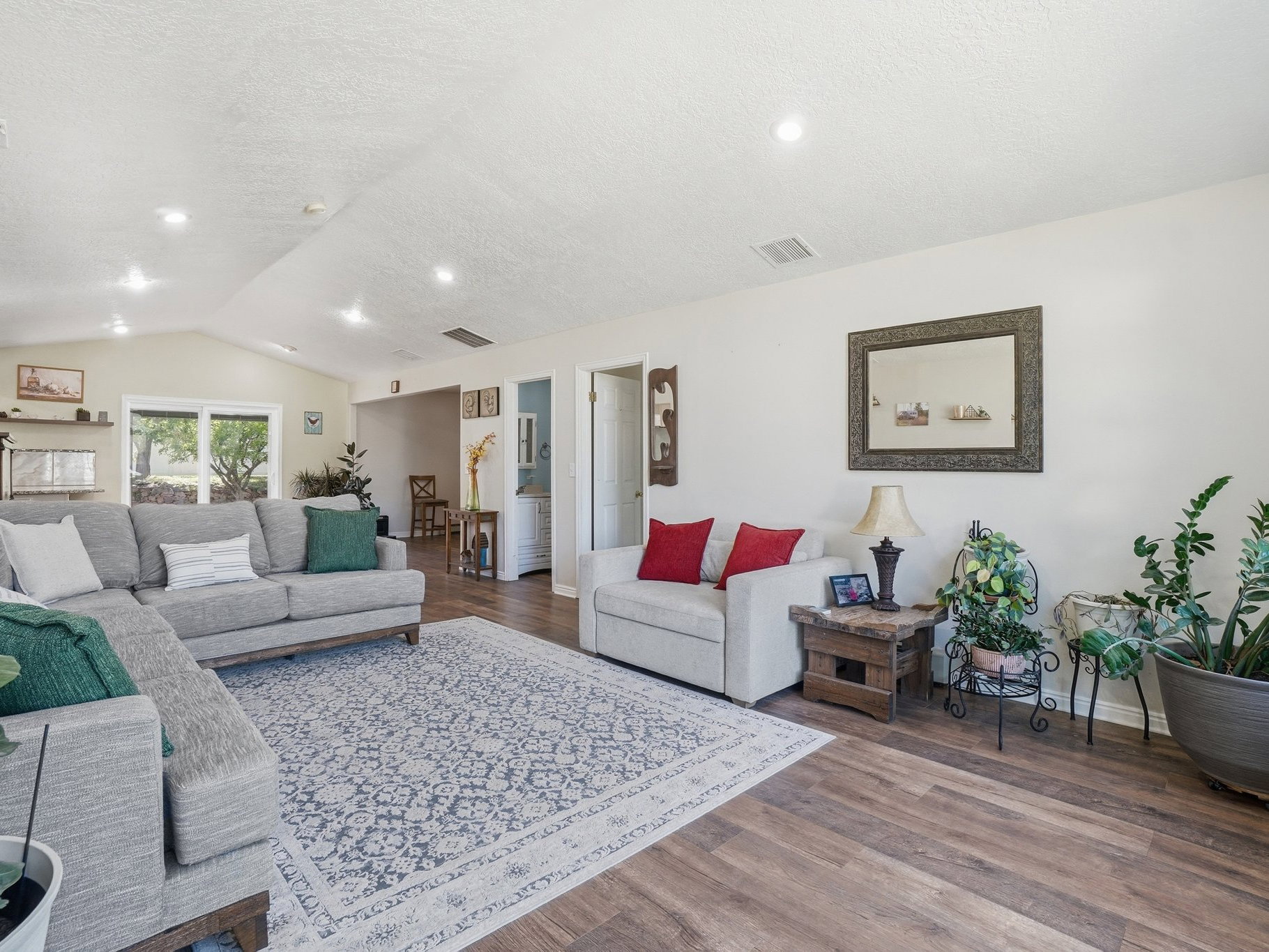 Spacious living area featuring wood-finish flooring, vaulted ceilings, and recessed lighting