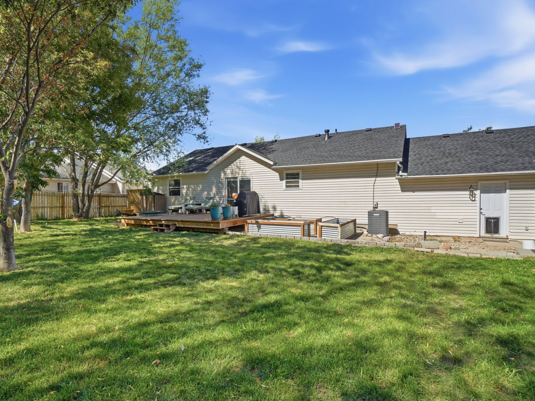 Expansive green lawn with mature trees and a multi-level wood deck