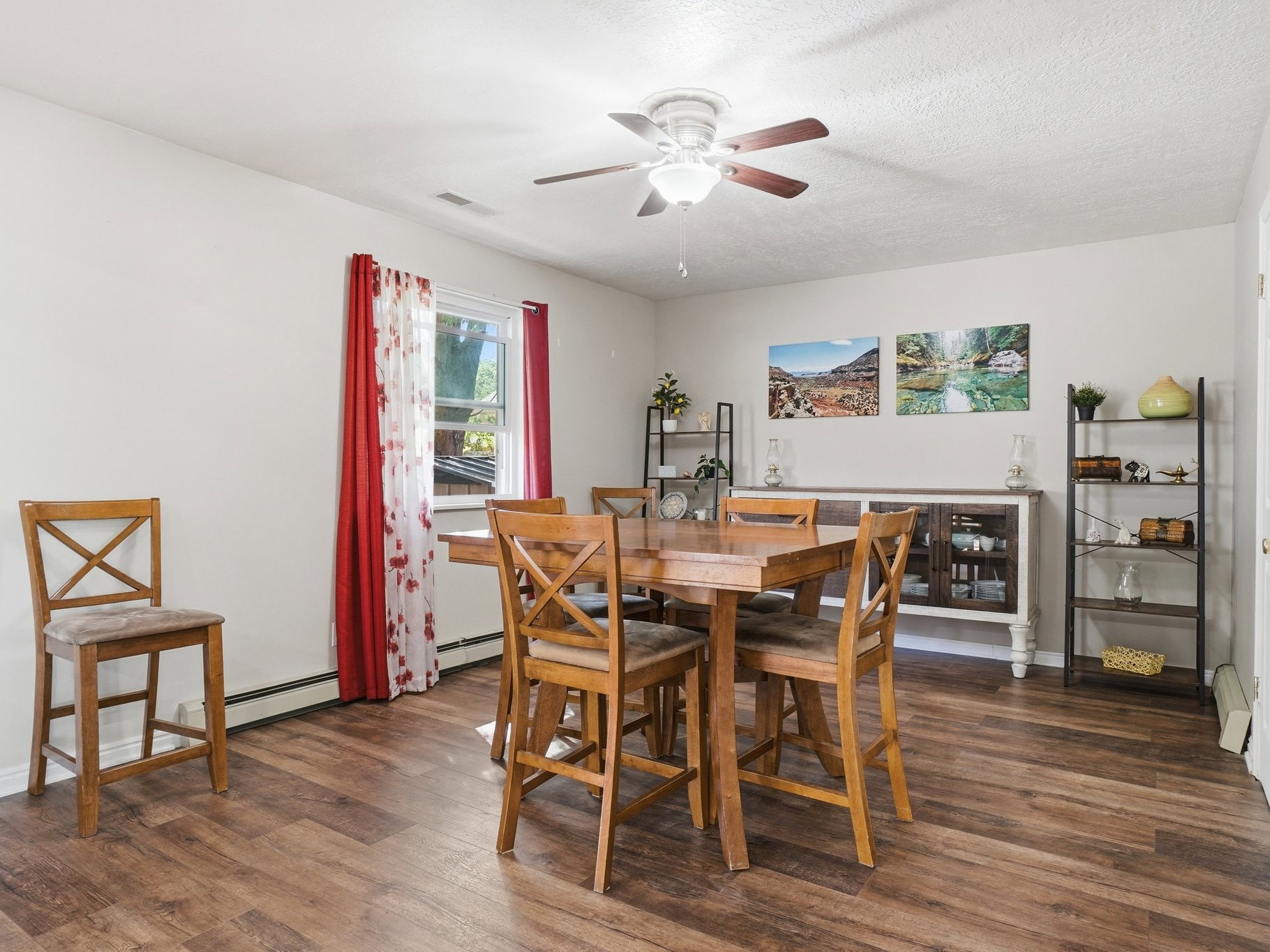 Spacious room featuring wood-finish flooring, a ceiling fan with light fixture, and light-toned walls