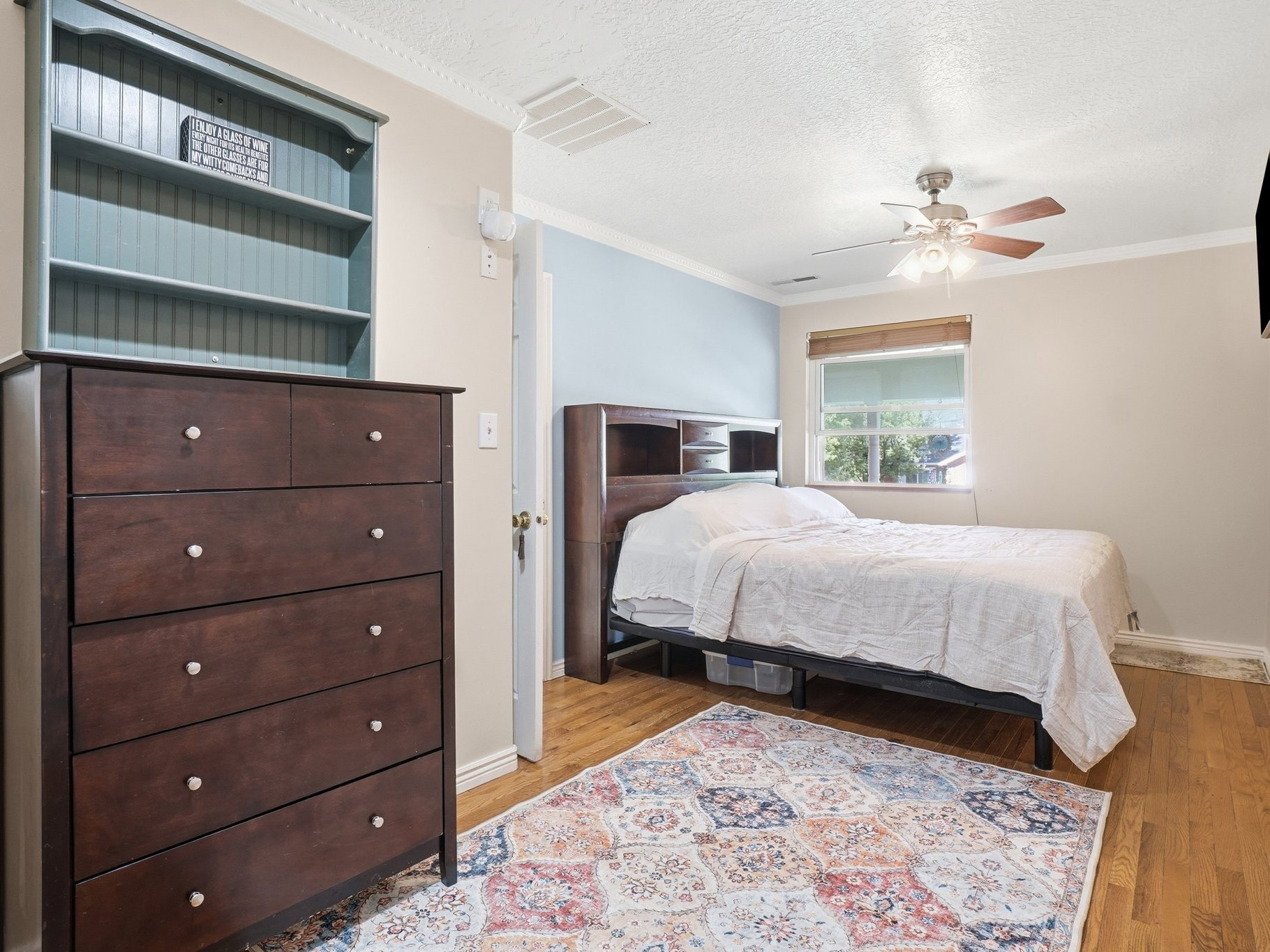 Bedroom featuring wood-finish flooring, a ceiling fan with light, and crown molding