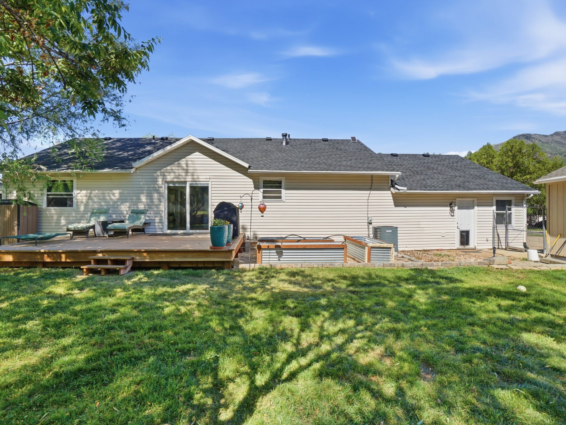 Spacious backyard featuring a large wood deck with steps, sliding glass patio doors, and a detached auxiliary structure