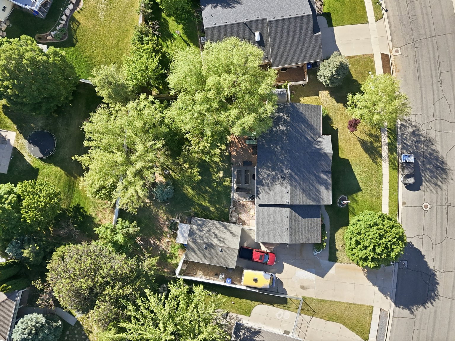Expansive residential property featuring a paved driveway, a large fenced backyard with mature trees, and a well-maintained lawn
