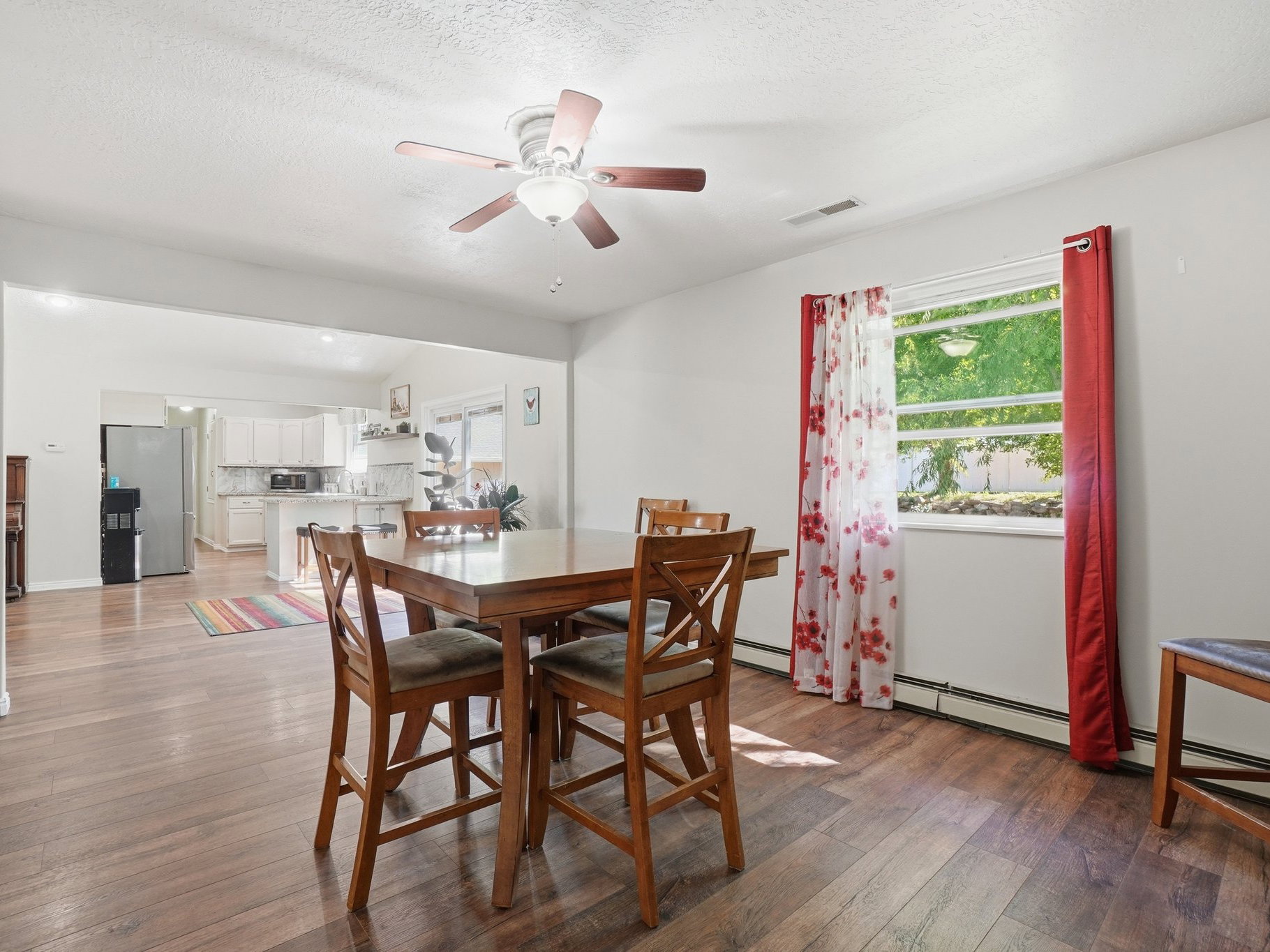 Dining area featuring wood-finish flooring, a ceiling fan with integrated lighting, and a large window
