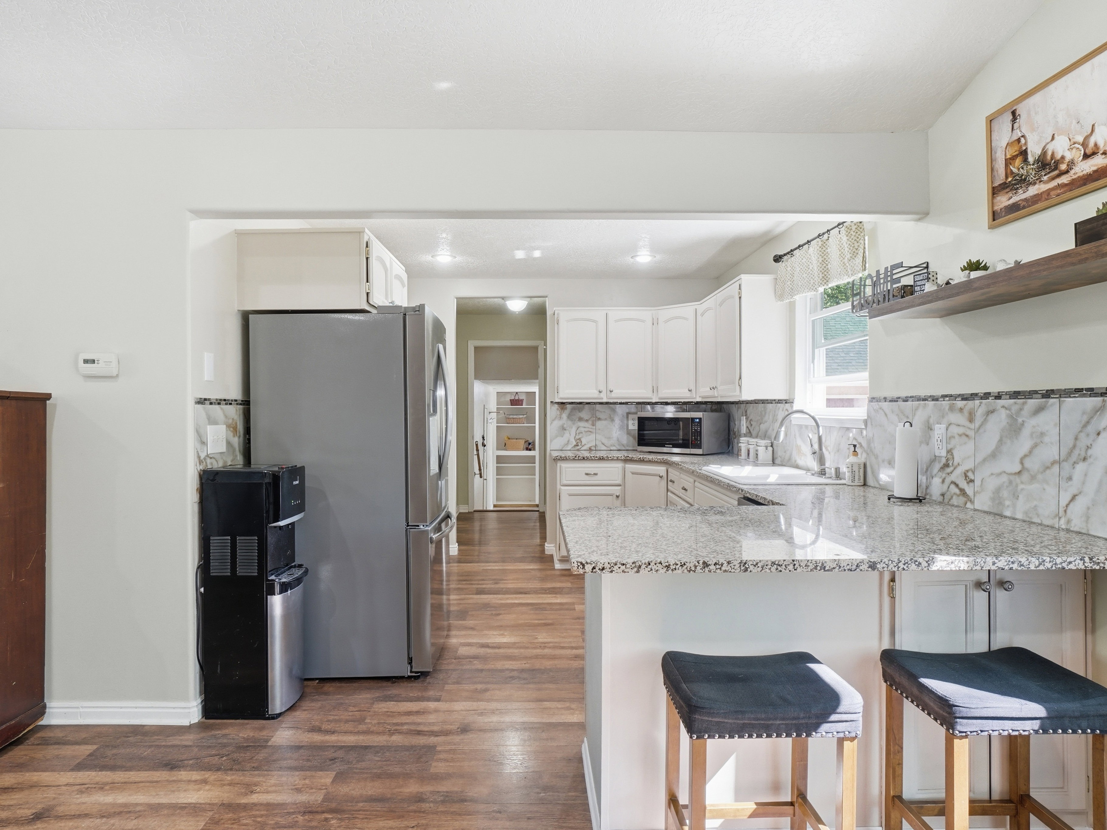 Kitchen featuring white cabinetry, granite countertops, white subway tile backsplash, and wood-finish flooring