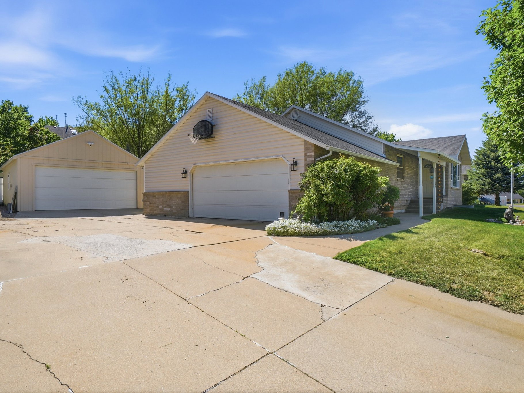 Exterior featuring a two-car attached garage, an additional two-car detached garage, stone facade accents, vinyl siding, and a concrete driveway