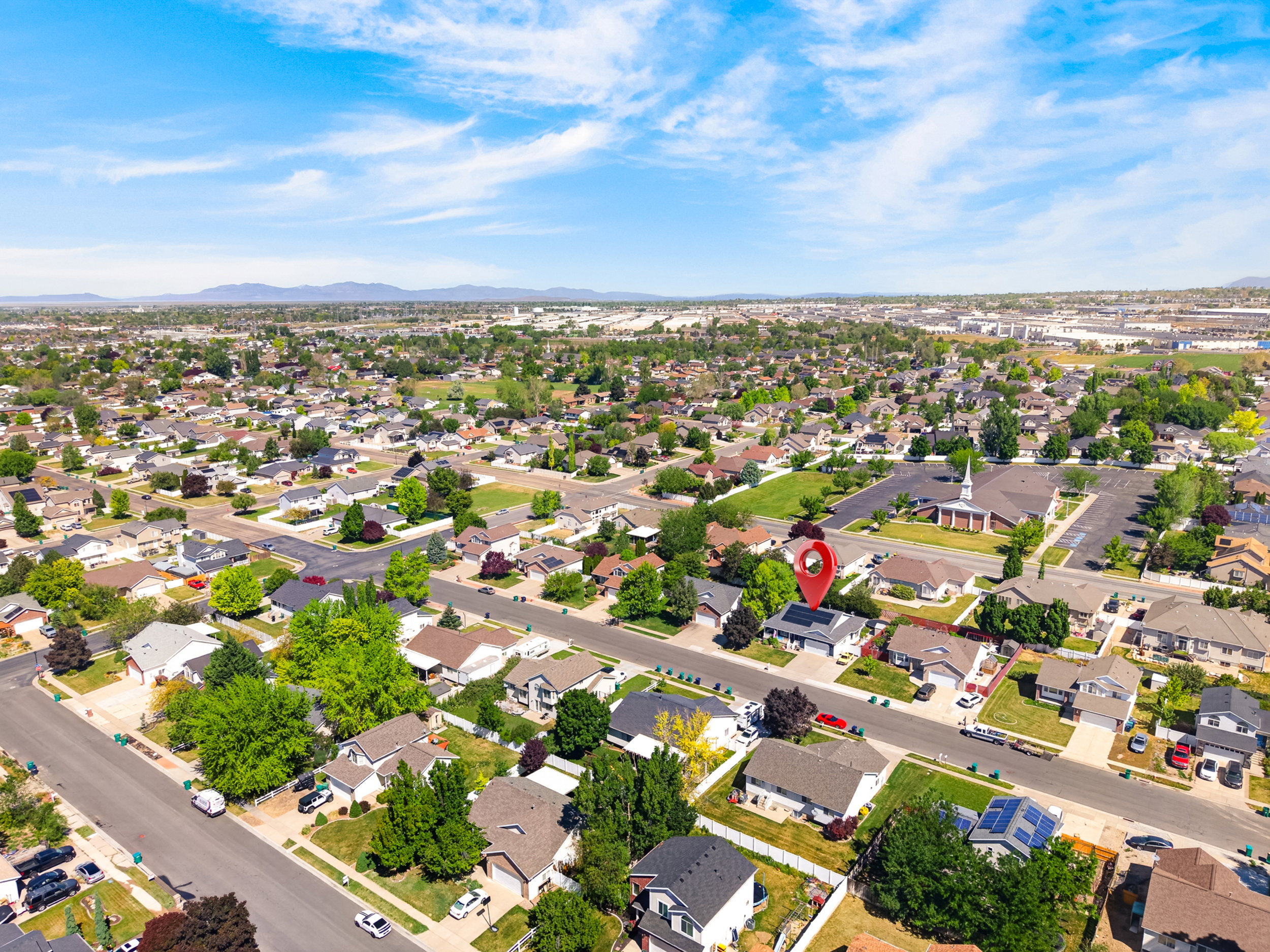 Suburban neighborhood with mature trees and a distant mountain range under a blue sky