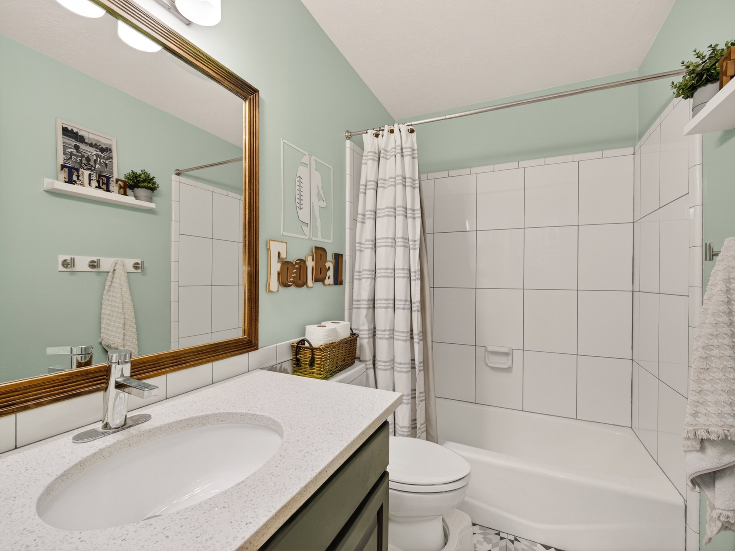 Bathroom featuring a white tile tub surround, white bathtub, and a built-in vanity with a light-colored countertop and undermount sink