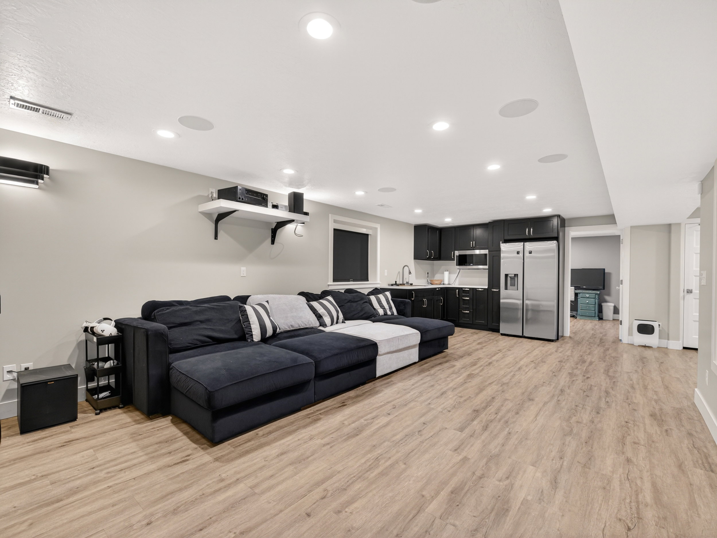 Spacious entertainment area featuring wood-finish flooring, recessed lighting, and built-in ceiling speakers