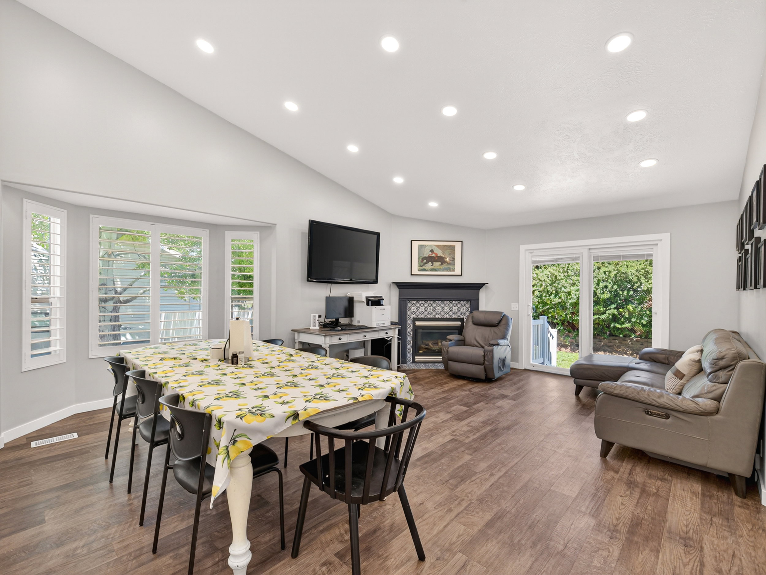 Spacious interior featuring a vaulted ceiling with recessed lighting, wood-finish flooring, and a bay window with plantation shutters