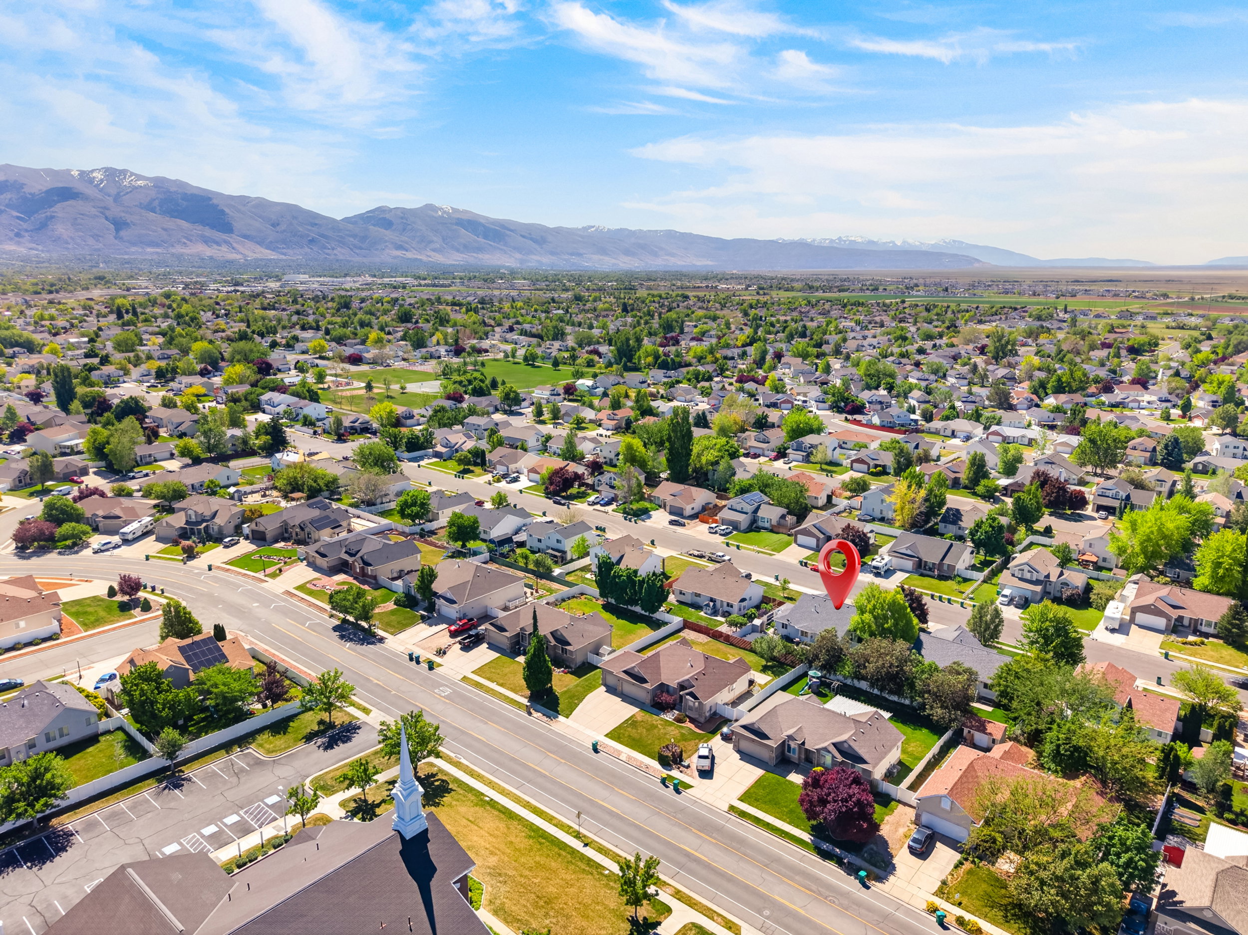 Residential neighborhood featuring single-story homes, mature trees, and mountain backdrop