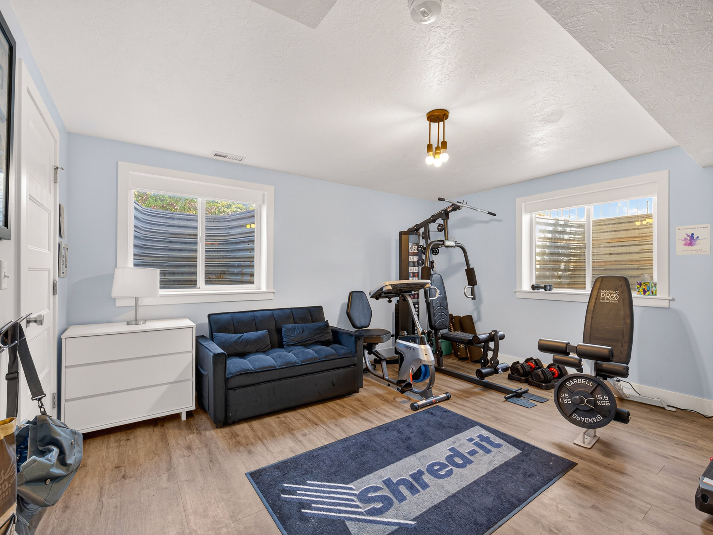 Spacious room featuring wood-finish flooring, two large egress windows, and a modern ceiling light fixture