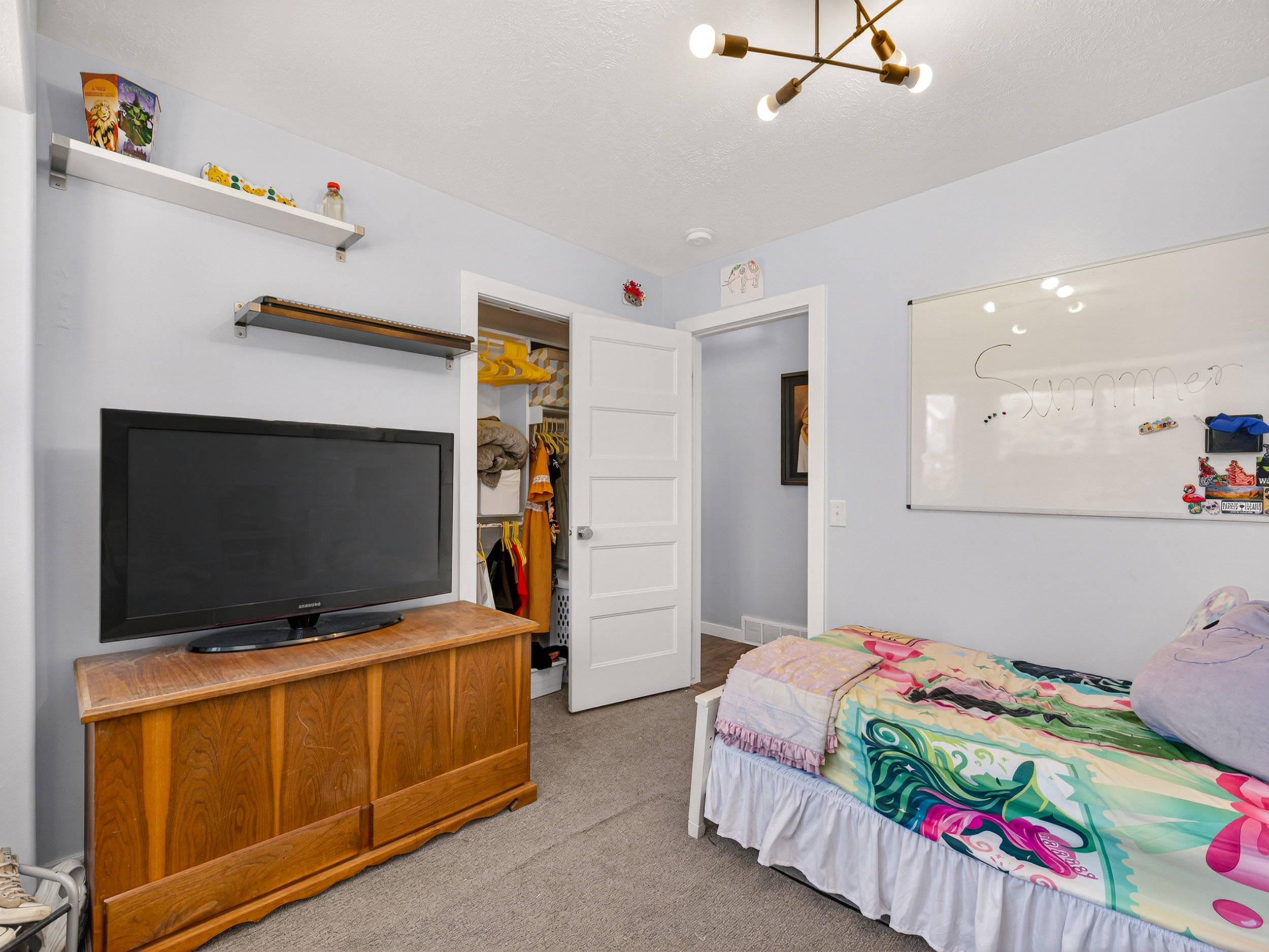 Bedroom featuring carpet flooring, a modern chandelier with exposed bulbs, and light blue wall paint