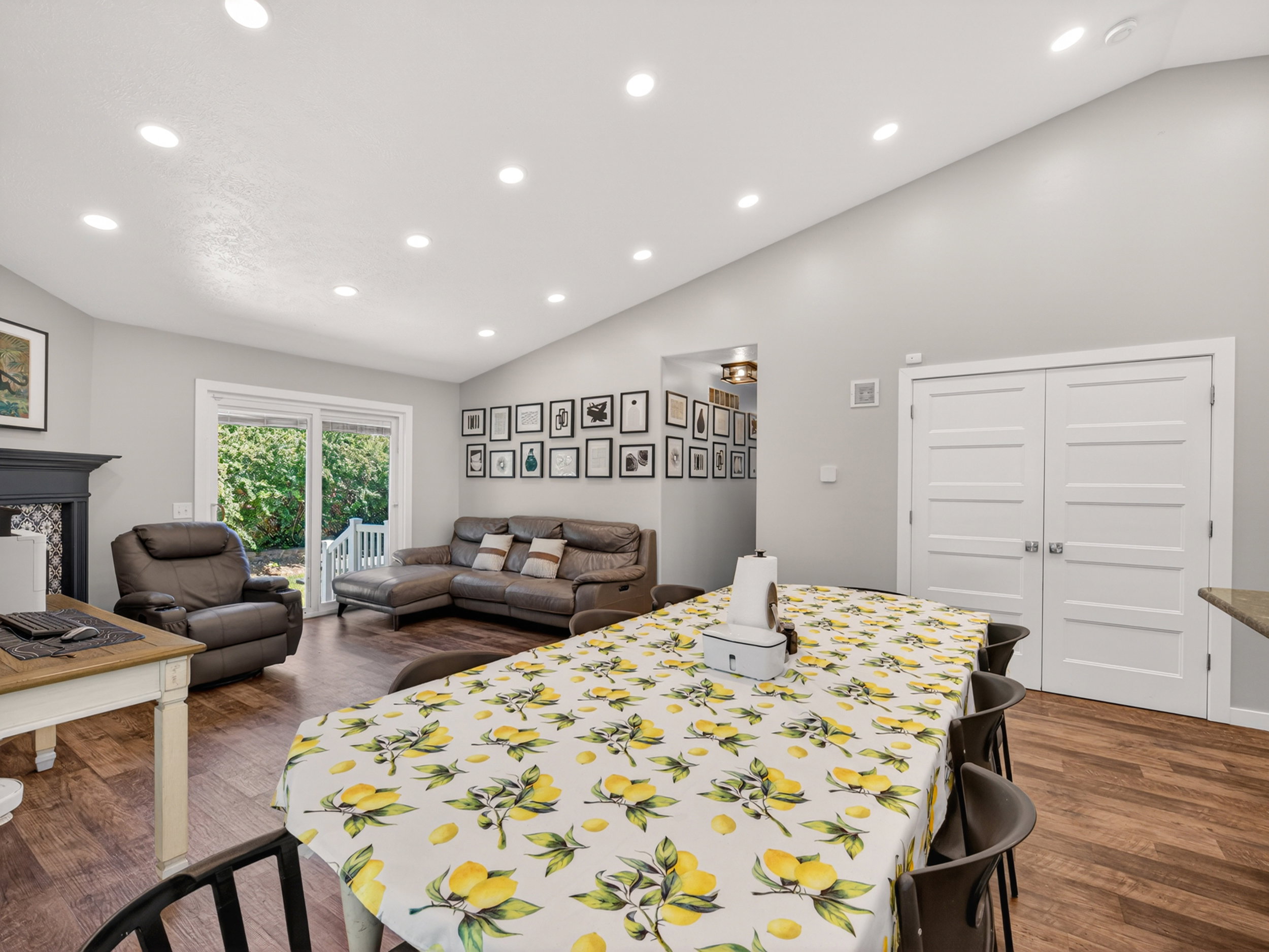 Open-concept living area with wood-finish flooring, vaulted ceiling, and recessed lighting